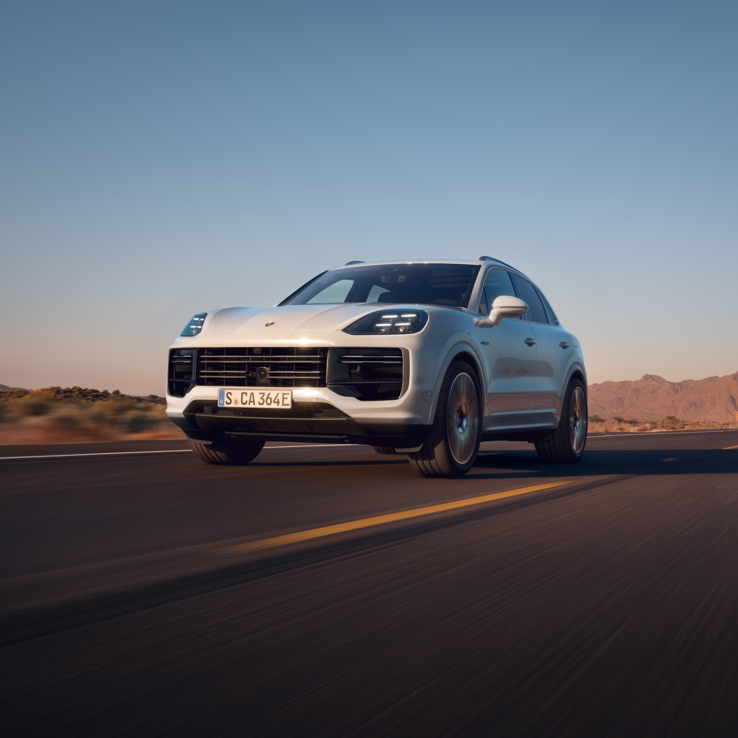 Un Porsche Cayenne conduciendo en una carretera abierta.